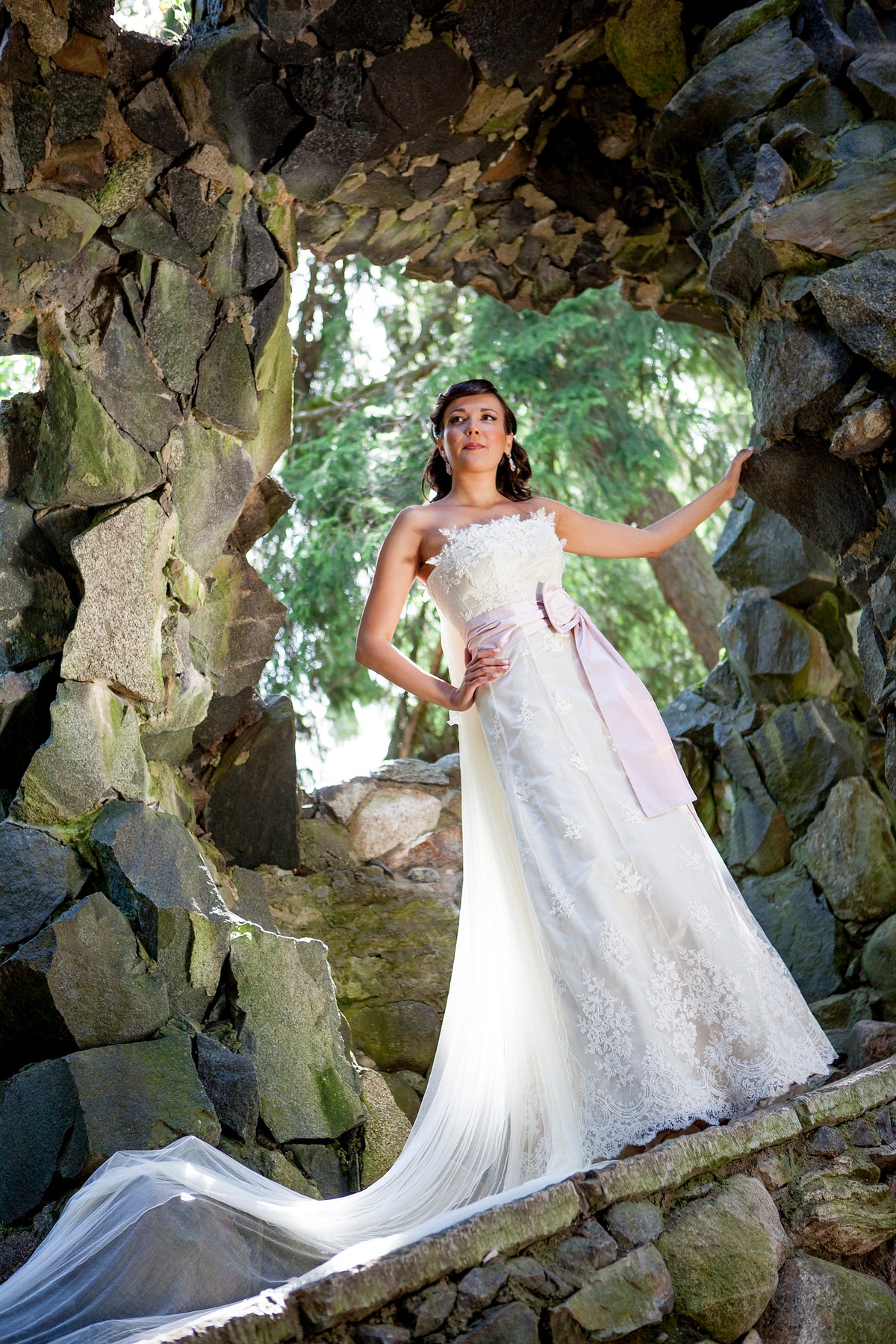 Bride in a strapless lace gown beneath a stone arch