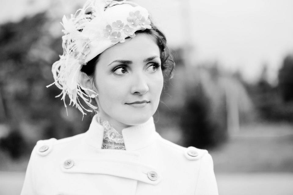 Bride wearing a tailored coat and feather headpiece