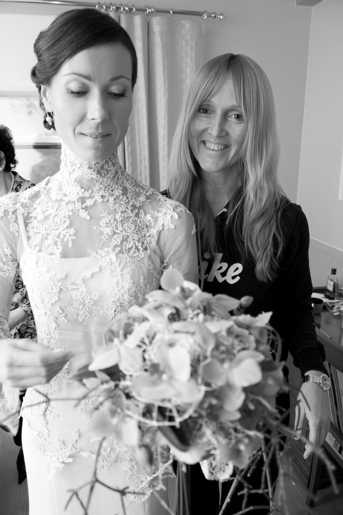 Bride in a lace gown standing beside a guest at her wedding