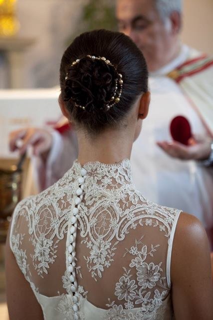 Close view of a bridal gown with a high lace collar, sheer back and covered buttons
