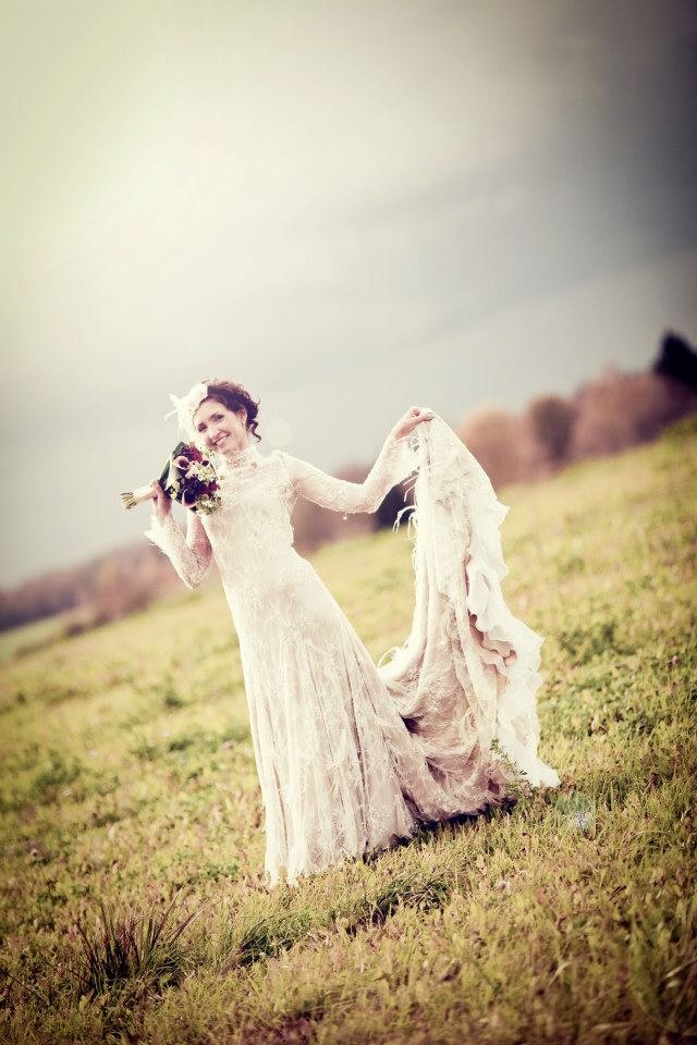 Bride outdoors in a long-sleeved lace gown with an open back and full train