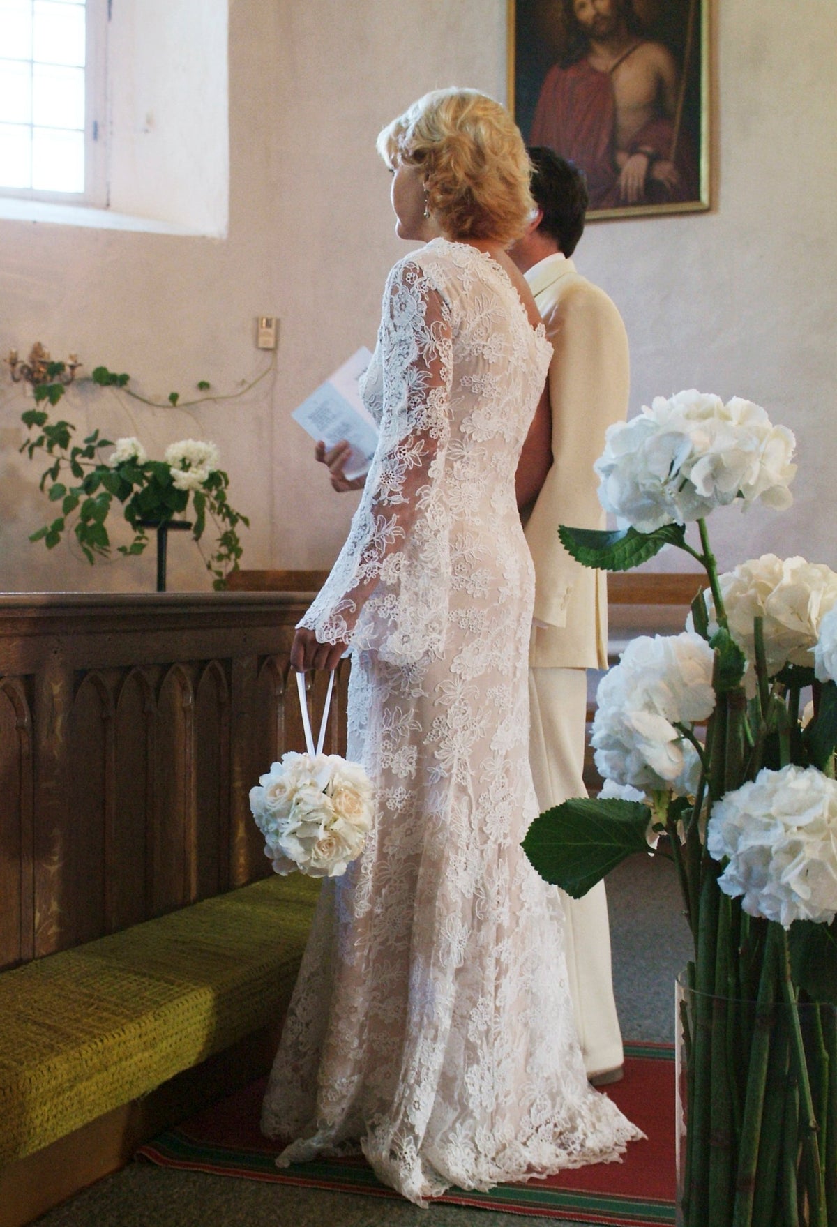 Bride in a long-sleeved lace gown with a fitted waist and train